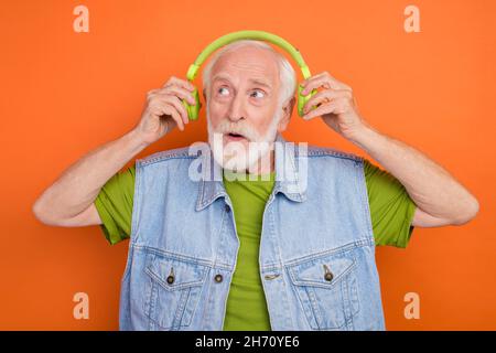Photo of shocked funny man pensioner dressed retro denim vest arms earphones looking empty space isolated blue color background Stock Photo