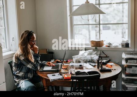 Woman using laptop in kitchen Stock Photo