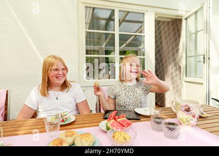 Girls sitting at table and eating Stock Photo
