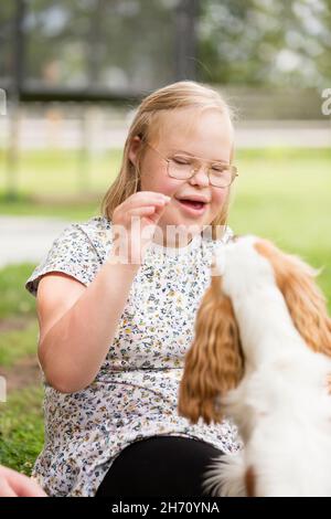 Smiling girl giving treat to dog Stock Photo