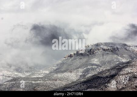 Ominous storm clouds and blowing snow over vast mountainscape Stock Photo