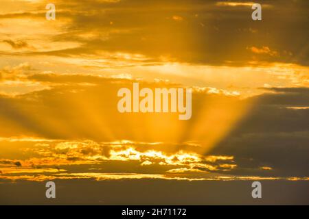 Golden rays of the sun break through clouds at sunrise to form the Tyndall Effect, Switzerland.. Stock Photo