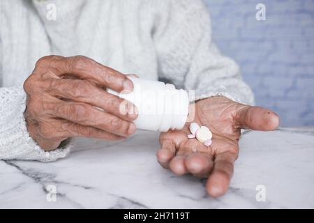 senior women taking medicine while sited  Stock Photo