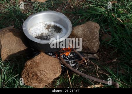 In a tourist hike in the cool autumn forest during the rest you need to make a fire, warm up, boil milk and brew tea from fresh herbs. Stock Photo