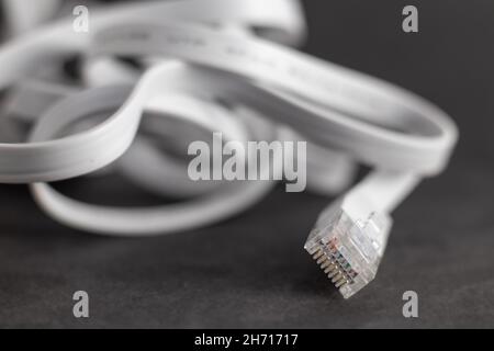 White flat ethernet ethernet cable with RJ-45 connector on gray background Stock Photo
