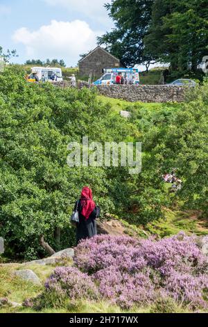 Derbyshire UK – 20 Aug 2020: A veiled woman looks up at the ice cream vans at Longshaw Estate, Peak District Stock Photo