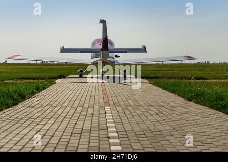A small private jet on the landing site before takeoff. Back view. Stock Photo
