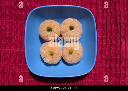 Delicious Orange shaped coconut ladoo sweets for festivals like Ganesh chaturthi, diwali. Coconut burfi with Orange shape and garnished with pista on Stock Photo