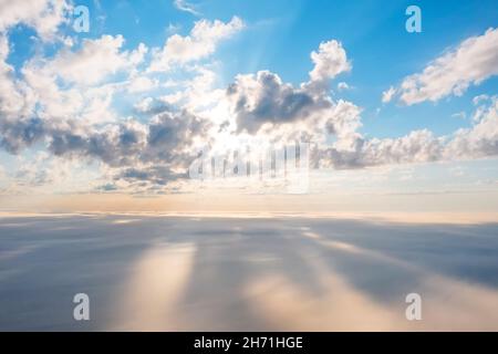 View at sunrise with puffy foggy. Cumulus summer clouds above. White puffy like cloud stretching to foggy horizon in the bright morning Stock Photo