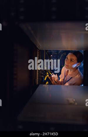 Caucasian female engineer inspecting the server in computer server room Stock Photo