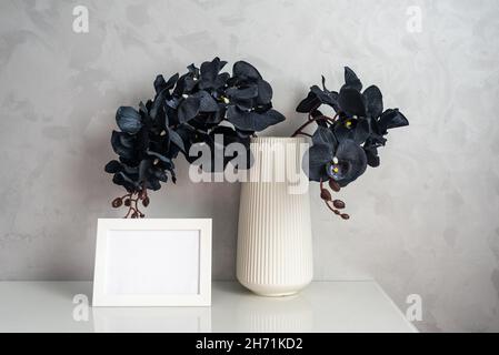 Orchid flowers with black petals and photoframe on cabinet Stock Photo