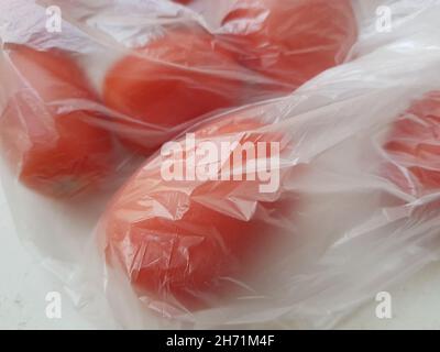 Closeup red tomatoes in a transparent cellophane bag. Stock Photo