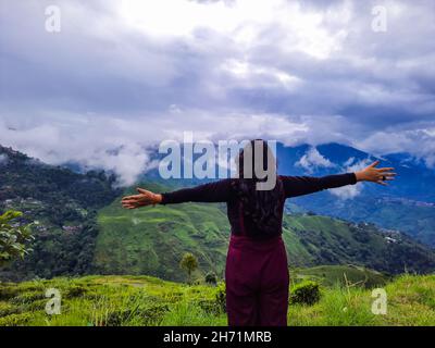 girl in victory pose at mountain top with dramatic sky at morning image is taken at darjeeling west bengal india 2h71mrb