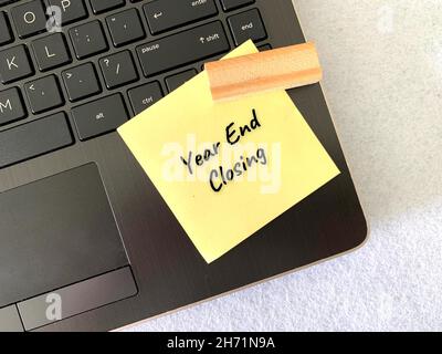 Year end closing text on sticky note with wooden brick and laptop background Stock Photo