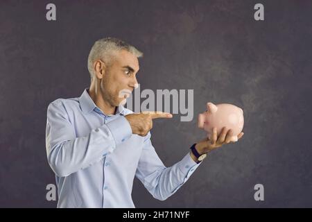 Middle-aged man make financial investments using piggybank Stock Photo