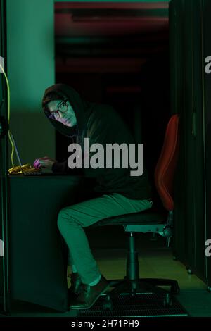Asian male hacker using a laptop in computer server room Stock Photo