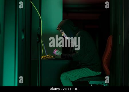 Asian male hacker using a laptop in computer server room Stock Photo