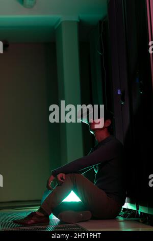 Asian man wearing vr headset while sitting in computer server room Stock Photo