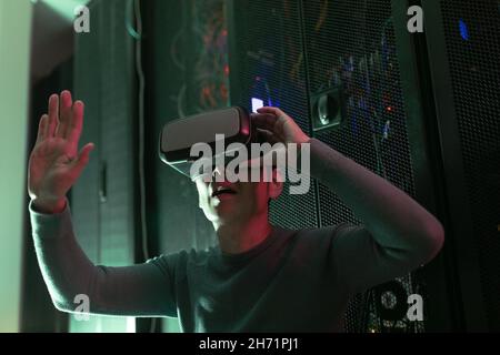Asian man wearing vr headset while sitting in computer server room Stock Photo