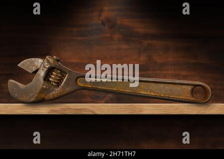 Closeup of an old rusty adjustable wrench on a wooden shelf. 19th century, Italy. Stock Photo