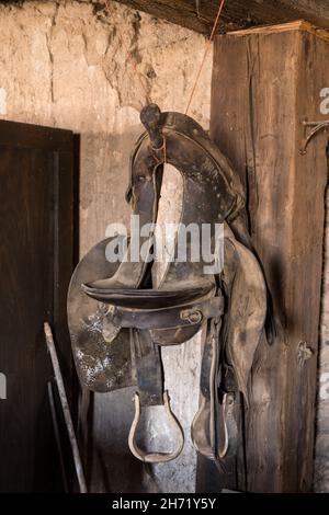 An old cavalry saddle hangs on the wall of the Grant House stagecoach station in Shakespeare, New Mexico. Stock Photo