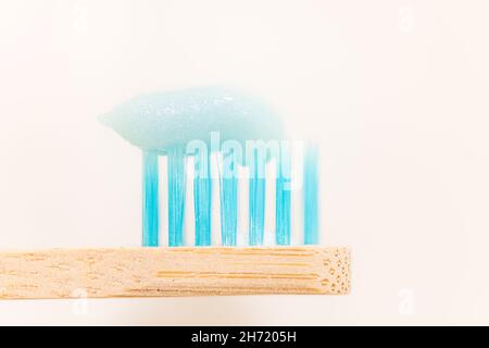 Close up blue toothpaste on wooden toothbrush over white background graphic resource for oral hygiene or dentistry Stock Photo