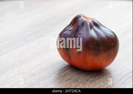 fresh picked multicolored striped and streaky purple, black, and red tomatoes on a wooden table Stock Photo