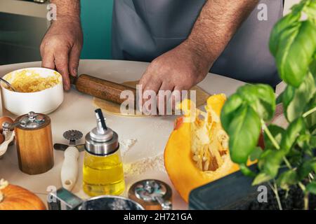 Staying at home and cooking. Homemade Italian pumpkin ricotta ravioli. Men rolling out ravioli dough. Stock Photo