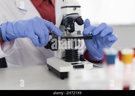 cropped view of scientist in latex gloves near microscope Stock Photo