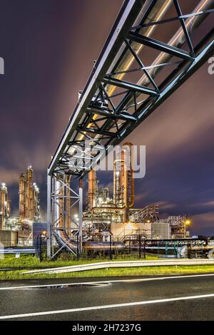 Scaffold with pipeline and Illuminated petrochemical production plant at nighttime, Port of Antwerp. Stock Photo