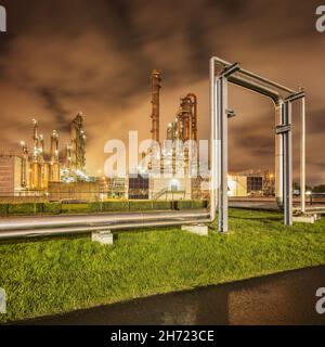 Construction with pipeline and Illuminated petrochemical production plant at twilight, Port of Antwerp. Stock Photo