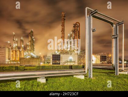 Construction with pipeline and Illuminated petrochemical production plant at twilight, Port of Antwerp. Stock Photo