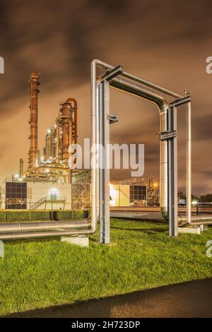 Construction with pipeline and Illuminated petrochemical production plant at twilight, Port of Antwerp. Stock Photo