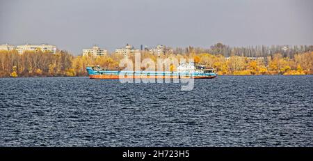 An articulated tug and bulk barge transport sand and construction materials along the river. A large barge sails along the wide Dnieper River. Transpo Stock Photo