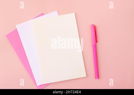 Colored blank sheets of pastel colors on a pink background next to the pen. Copy space Stock Photo