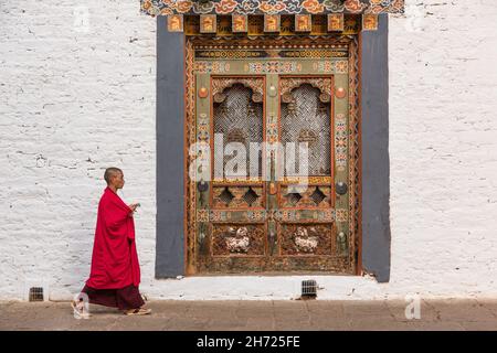 Buddhist monk walks past a window of monastery in Bhutan Stock Photo ...