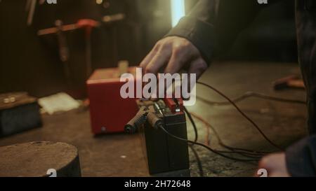 Young electrician measuring battery values with ammeter close-up Stock Photo