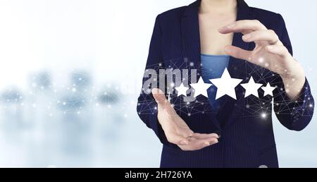 Customer Experience Concept. Two hand holding virtual holographic five stars icon with light blurred background. Business satisfaction survey Stock Photo