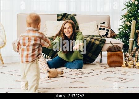 Child takes his first steps as his mother supports, ready to catch him. Stock Photo