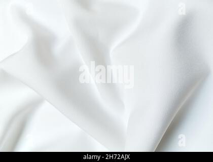 White crumpled or wavy fabric texture background. Abstract linen cloth soft waves. Creases of satin, silk, and cotton. Smooth elegant silk or atlas Stock Photo