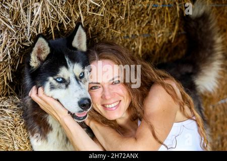 Beautiful red-haired woman hugging the husky. High quality photo Stock Photo