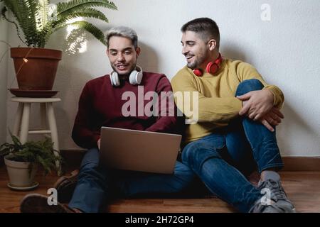 Gay men couple having fun using laptop computer at home - Focus on right male face Stock Photo