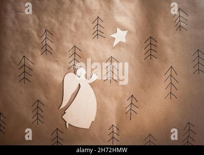 Hand made wooden angel and star on brown paper background. Minimal eco Christmas concept. Stock Photo