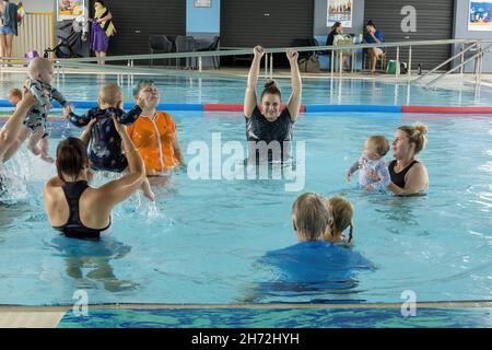 MACKAY, AUSTRALIA - Oct 22, 2021: A closeup of women with their babies in water giving swimming lessons at an aquatic center