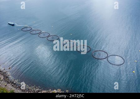 Aerial view of a salmon farm, rainy weather, grey sky, village Myre in the back, Vesteralen islands, Norway Stock Photo