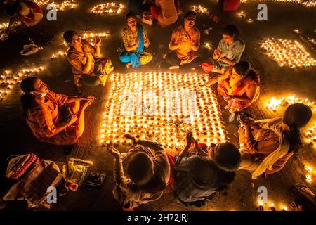 Kolkata, West Bengal, India. 19th Nov, 2021. The Dev Deepavali (''the Diwali of the Gods'' or ''Festival of Lights of the Gods'') falls on the Kartik Poornima and is celebrated in Kolkata, India. Kartik Purnima means the full moon on the Hindu month of Kartika and it takes place fifteen days after Diwali. Women & Children lighting earthen oil lamps at a riverbank, as a prayer offering to the river Ganges. The diyas are lit to welcome the Gods, who, it is believed, descend to bathe in the river Ganga in Kashi on this day. (Credit Image: © Saurabh Sirohiya/ZUMA Press Wire) Credit: ZUMA Press, In Stock Photo