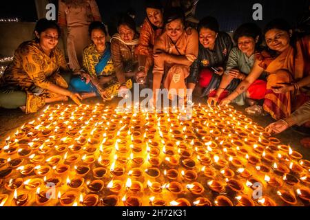 Kolkata, West Bengal, India. 19th Nov, 2021. The Dev Deepavali (''the Diwali of the Gods'' or ''Festival of Lights of the Gods'') falls on the Kartik Poornima and is celebrated in Kolkata, India. Kartik Purnima means the full moon on the Hindu month of Kartika and it takes place fifteen days after Diwali. Women & Children lighting earthen oil lamps at a riverbank, as a prayer offering to the river Ganges. The diyas are lit to welcome the Gods, who, it is believed, descend to bathe in the river Ganga in Kashi on this day. (Credit Image: © Saurabh Sirohiya/ZUMA Press Wire) Credit: ZUMA Press, In Stock Photo