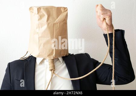 business man with a paper bag on it's head, and a jute rope around his neck Stock Photo