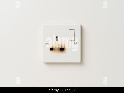 Damaged electrical domestic power socket with cracks and burn marks Stock Photo