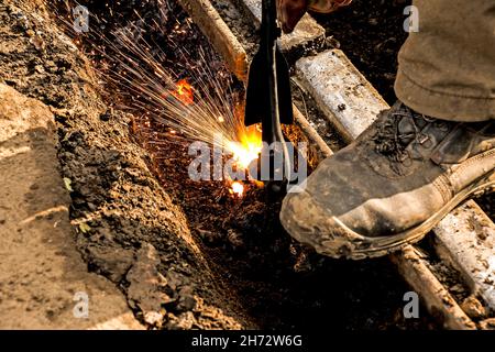 Close-up of the hand of an industrial worker working on the process of cutting rails. A male worker cuts steel using a plasma cutter. Stock Photo